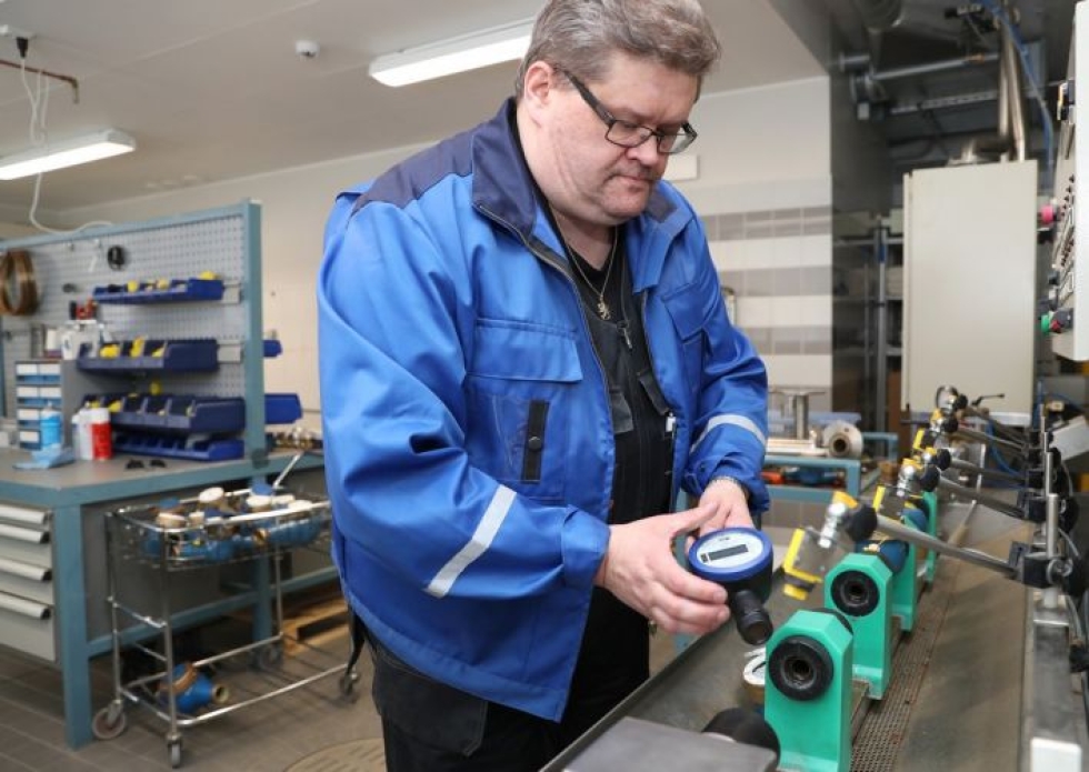 Joensuun Veden laitosasentaja Jarkko Keinänen laittaa vesimittarit testipenkkiin. Kädessään hänellä uusi etäluettava digitaalinen vesimittari.