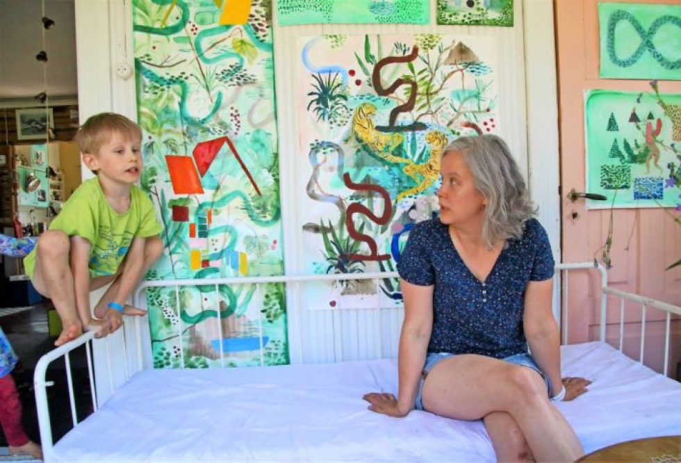 Kaisa Jussila on kutsunut kotiinsa, vanhalle maatilalle, taiteilijaystäviään yhteiseen näyttelyyn. Kuvassa hänen lapsensa Jalmari Väisänen ja taustalla Satu Rautiaisen maalaukset.