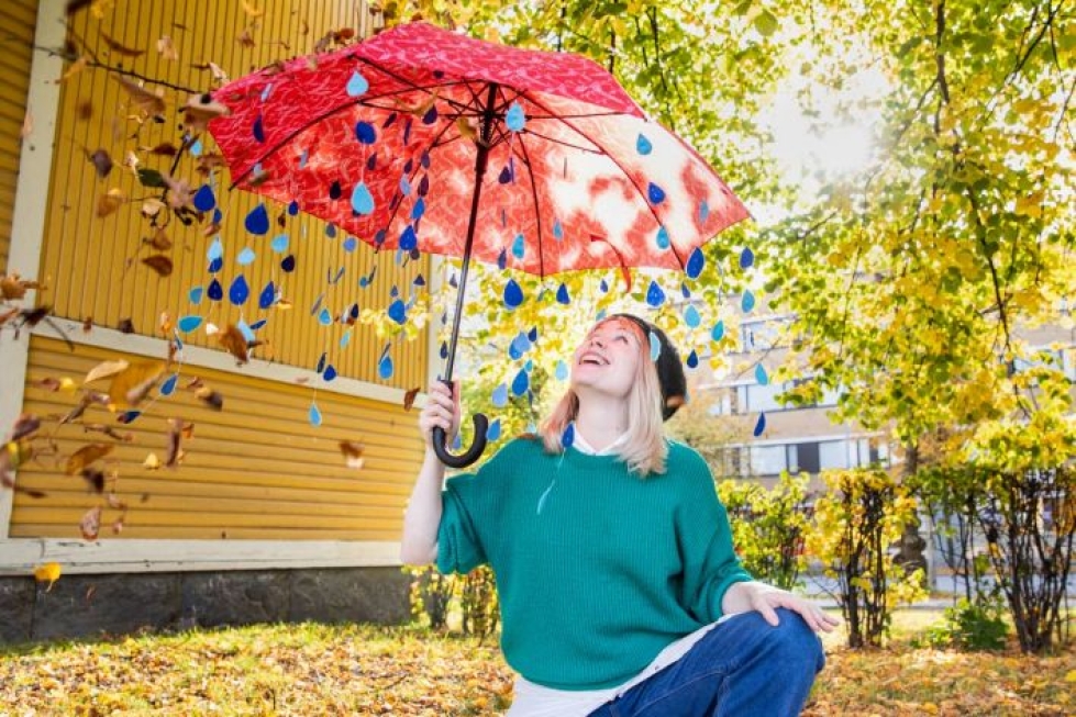 Sanna Kärkkäinen jalkautuu festivaalin aikaan ihmisten pariin kuvataiteilija Riikka Mattisen koristeleman sateenvarjon kera.
