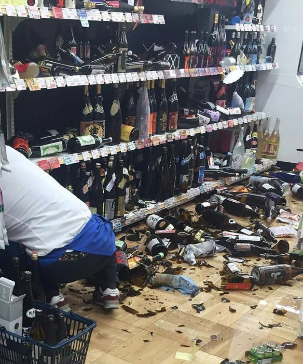Kaupan työntekijä siivosi rikkoutuneita viinipulloja maanjäristyksen jälkeen Japanin Kumamotossa. LEHTIKUVA/AFP