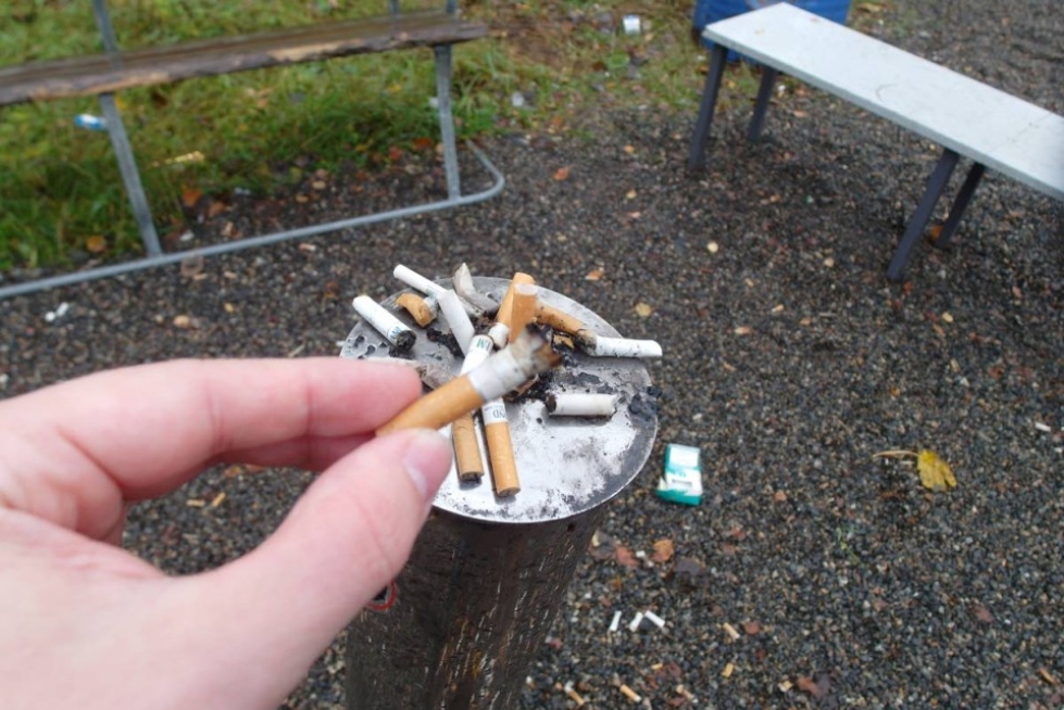 Tupakkapaikka Tulliportinkadun Pohjois-Karjalan ammattiopiston H-rakennuksen takana. Opiskelijat käyttävät aina käsineitä siivotessaan tupakkapaikkaa.