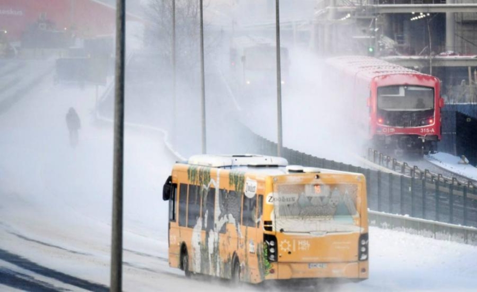 Pyöräilijä, linja-auto ja metrojuna lumimyräkässä Helsingissä 4. tammikuuta tänä vuonna.