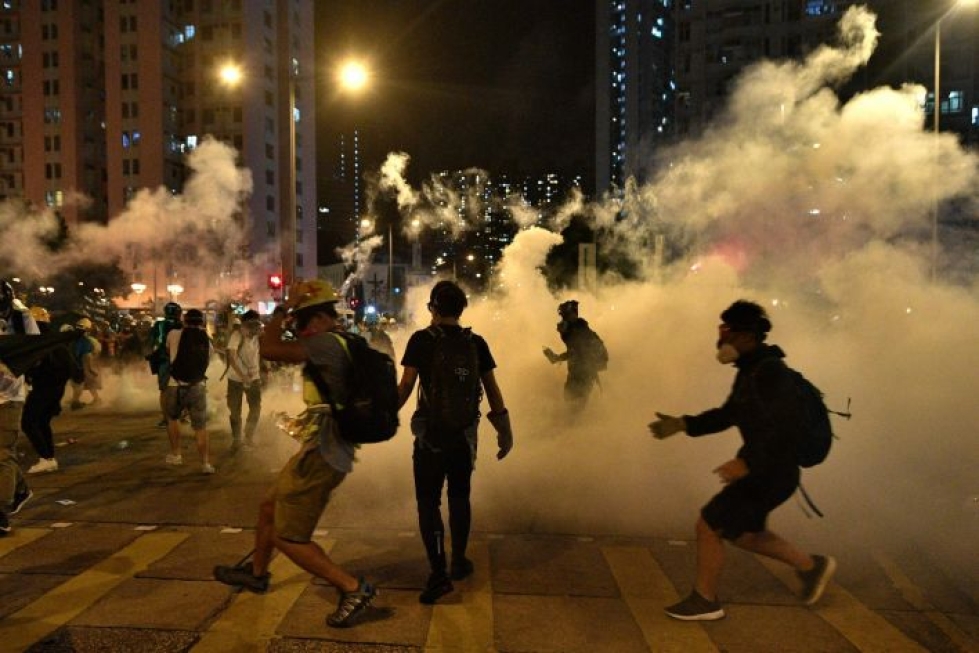 Poliisi käytti kyynelkaasua ja patukoita hajottaakseen kypäriin ja kaasunaamareihin sonnustautuneiden mielenosoittajien tuhatpäisen joukon. LEHTIKUVA/AFP